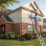 Technician cleaning the siding of a two-story home